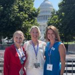 Three people smile and pose for a photo outside of the U.S. Capital Building in Washington, D.C.