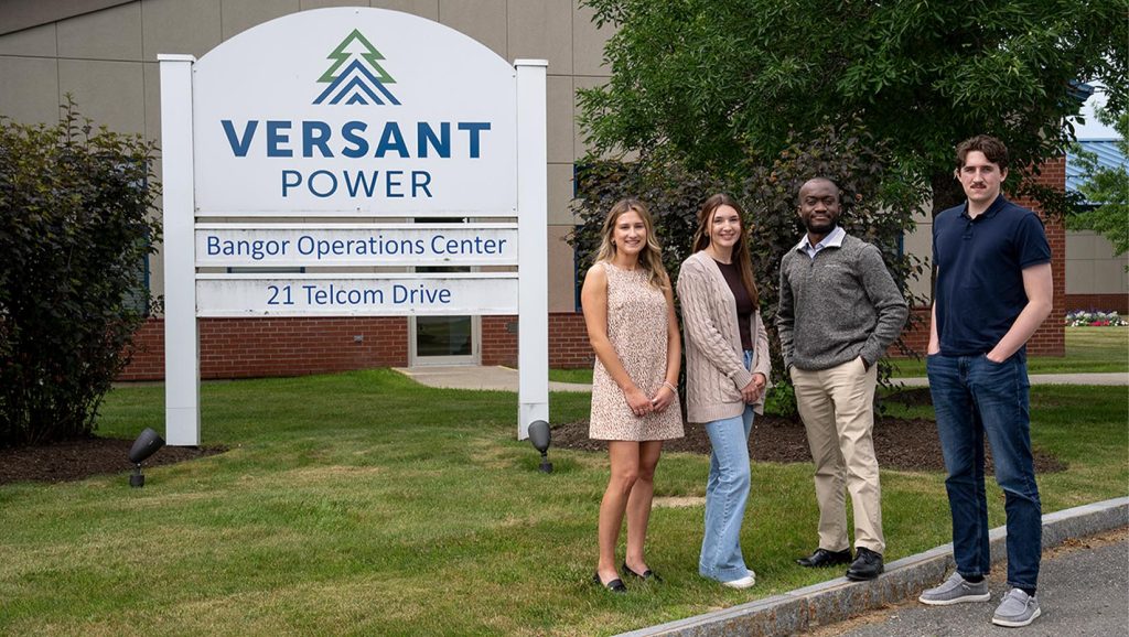 Four people pose for a photo outside of the Versant Power Bangor Operations Center.