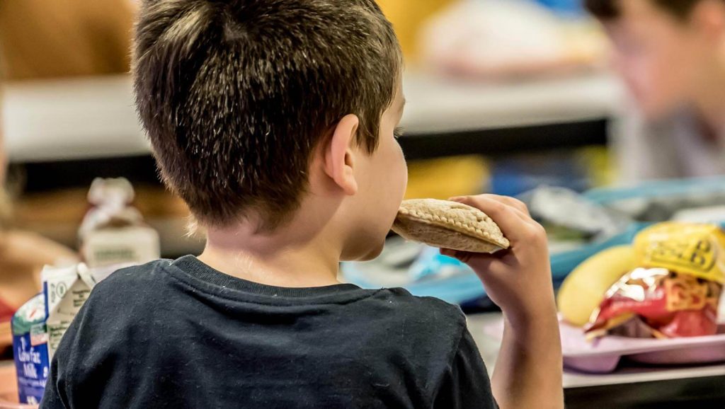 A photo of a child eating lunch at a school